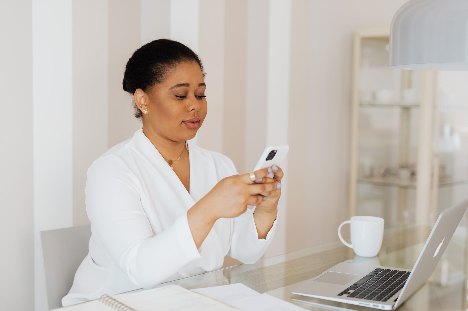 Young Zimbabwean businesswoman working on smartphone at organised desk
